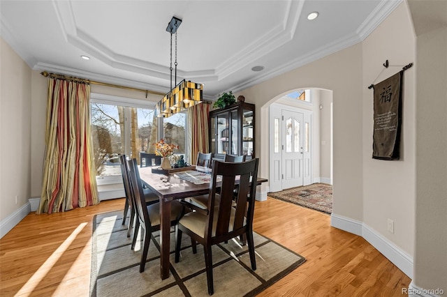 dining room with crown molding, light hardwood / wood-style flooring, and a raised ceiling