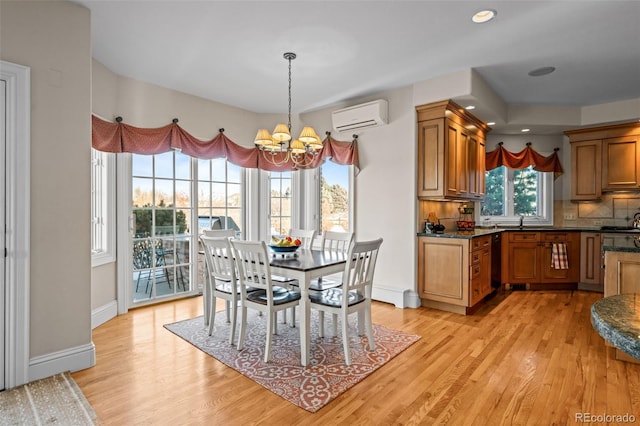 dining space with sink, a wall mounted AC, a chandelier, and light hardwood / wood-style floors