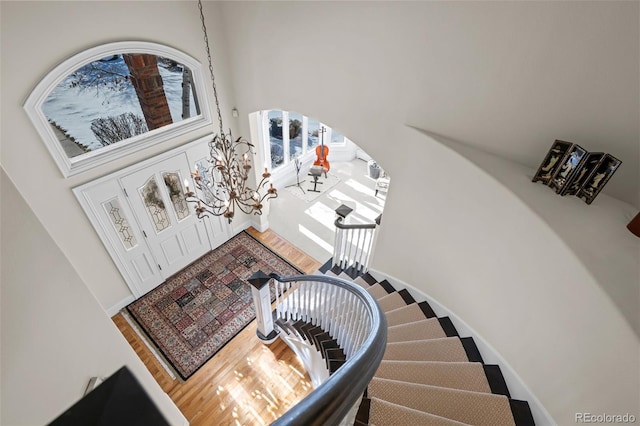 staircase with a towering ceiling and hardwood / wood-style flooring