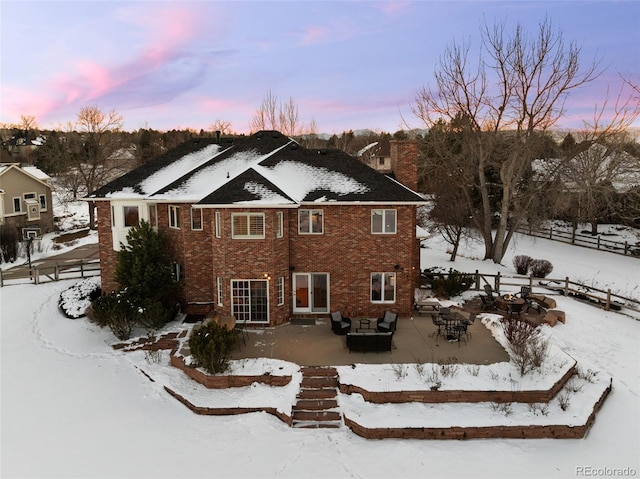 snow covered back of property with a patio