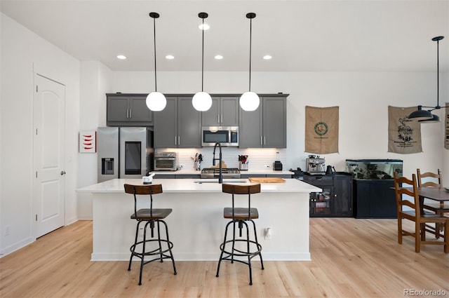 1929 W 165th Way, Broomfield, CO 80023 - kitchen featuring stainless steel appliances, light countertops, an island with sink, light wood-type flooring, and recessed lighting