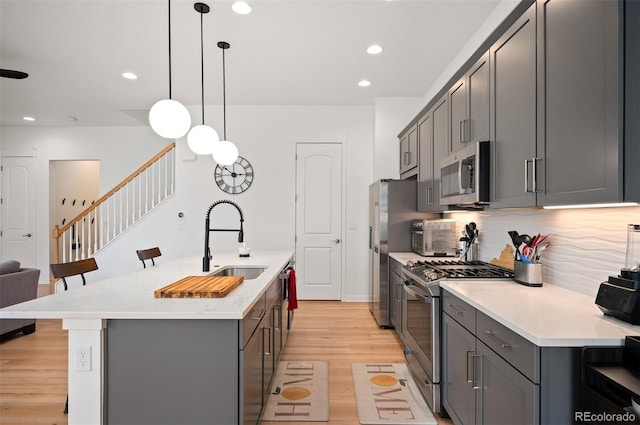 1929 W 165th Way, Broomfield, CO 80023 - kitchen with stainless steel appliances, a sink, gray cabinets, a kitchen island with sink, and light wood-style floors