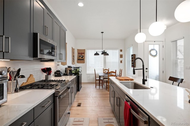 1929 W 165th Way, Broomfield, CO 80023 - kitchen with appliances with stainless steel finishes, a sink, light wood-type flooring, decorative backsplash, and decorative light fixtures