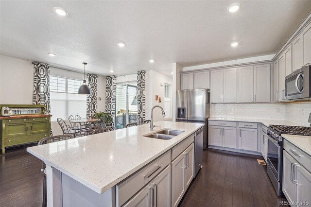 kitchen featuring appliances with stainless steel finishes, dark wood-type flooring, a kitchen island with sink, and sink