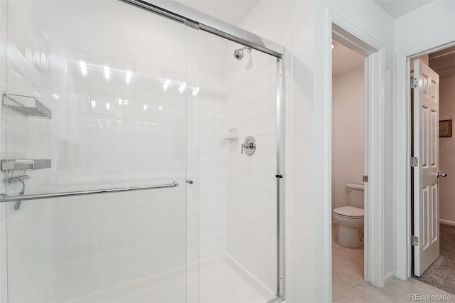 bathroom with tile patterned flooring, toilet, and a shower with door