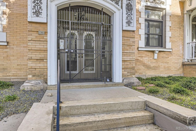 doorway to property with brick siding and a gate