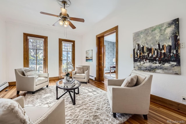 living area featuring a baseboard radiator, ceiling fan, wood finished floors, and baseboard heating