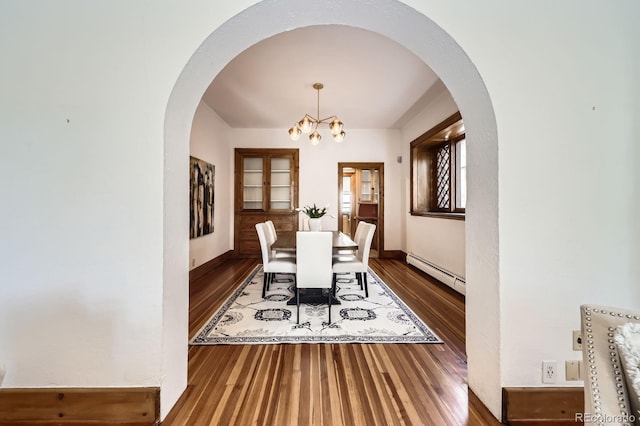 dining room featuring a baseboard heating unit, wood finished floors, a chandelier, arched walkways, and baseboards