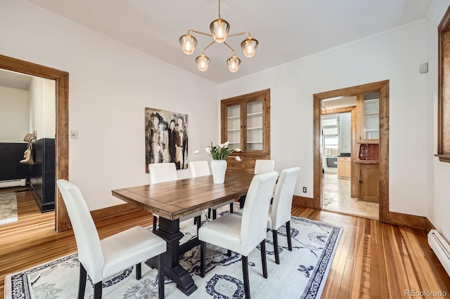 dining space with light wood finished floors, baseboard heating, a chandelier, baseboards, and ornamental molding