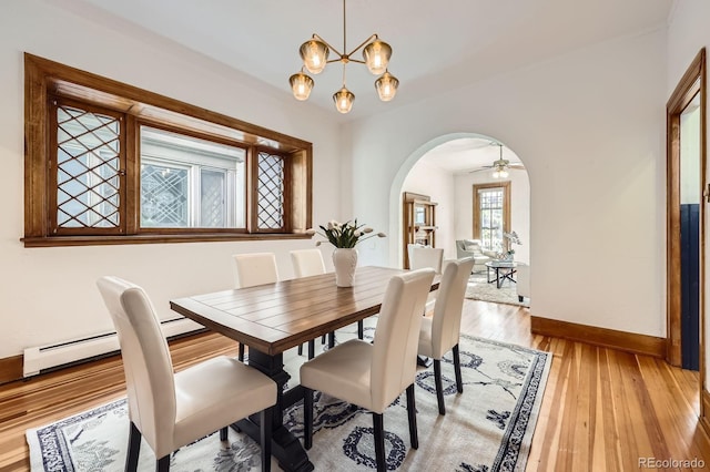 dining space with arched walkways, baseboards, light wood-style flooring, a chandelier, and a ceiling fan