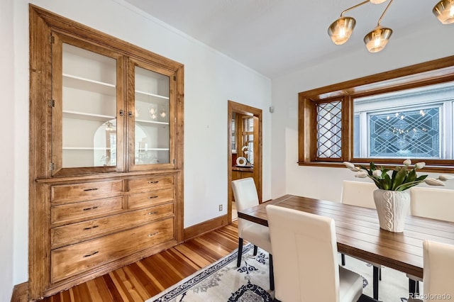 dining area featuring wood finished floors, baseboards, and crown molding