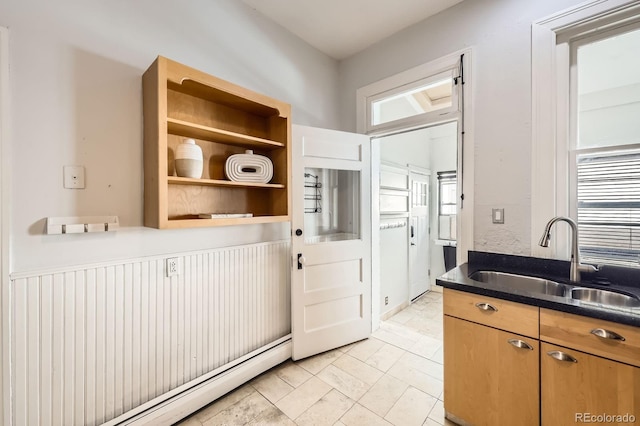 kitchen with a sink, baseboard heating, and dark countertops