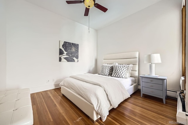 bedroom featuring wood finished floors, a ceiling fan, baseboards, and a baseboard heating unit