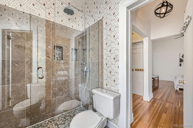 full bath with a shower stall, wood finished floors, toilet, and baseboards