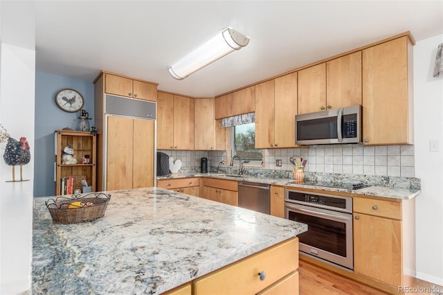 6905 Nelson St, Arvada, CO 80004 - kitchen featuring decorative backsplash, light brown cabinetry, light stone counters, light wood finished floors, and stainless steel appliances
