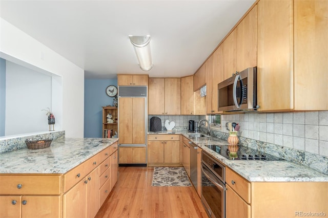 6905 Nelson St, Arvada, CO 80004 - kitchen featuring light stone counters, appliances with stainless steel finishes, a sink, light wood-style floors, and backsplash
