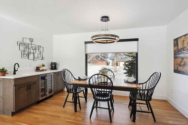 dining area featuring indoor wet bar, beverage cooler, and light hardwood / wood-style floors