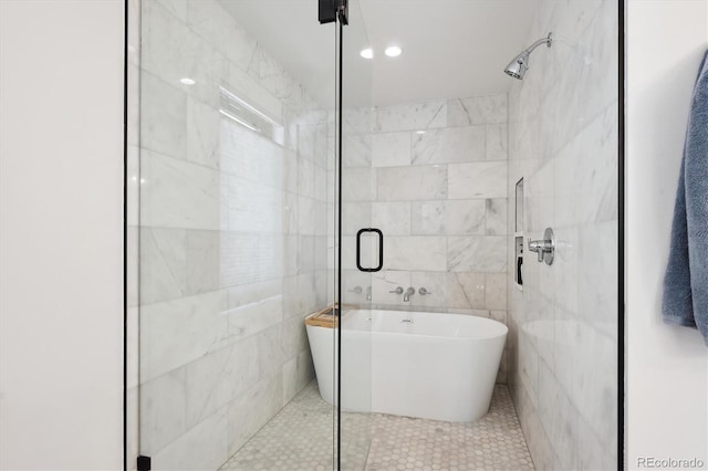 bathroom featuring tile patterned flooring, a bath, and tile walls