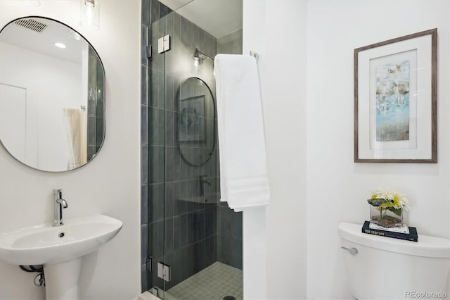 bathroom with sink, a shower with door, and toilet