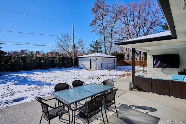 snow covered patio featuring a garage, an outdoor structure, and an outdoor hangout area