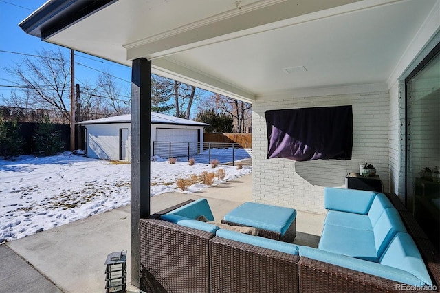 snow covered patio with a shed, a garage, and an outdoor hangout area