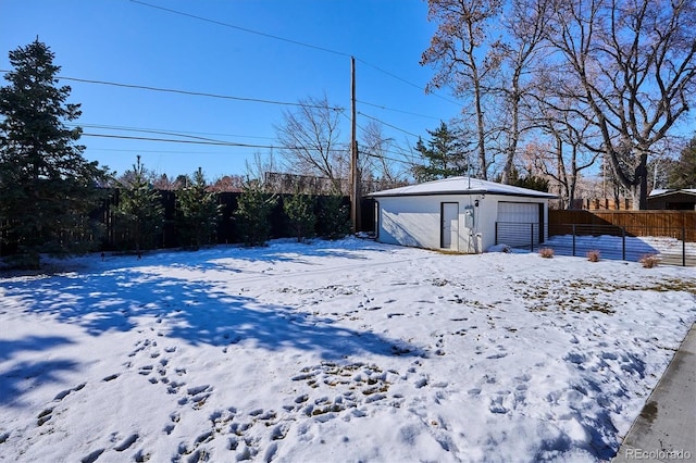 snowy yard featuring an outbuilding and a garage