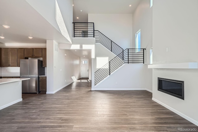 kitchen featuring dark wood-style floors, baseboards, freestanding refrigerator, light countertops, and open floor plan