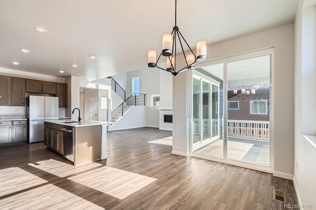 kitchen featuring visible vents, a sink, backsplash, freestanding refrigerator, and light countertops