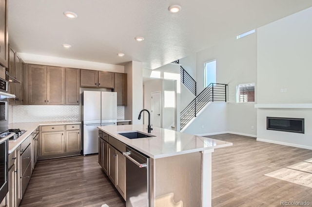 kitchen with wood finished floors, stainless steel appliances, light countertops, and a sink