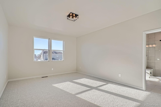 unfurnished bedroom featuring visible vents, baseboards, ensuite bathroom, and carpet