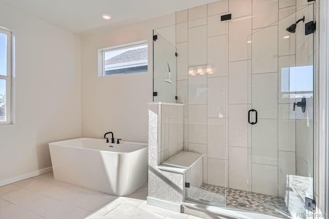 full bath featuring baseboards, a freestanding bath, a shower stall, and tile patterned flooring