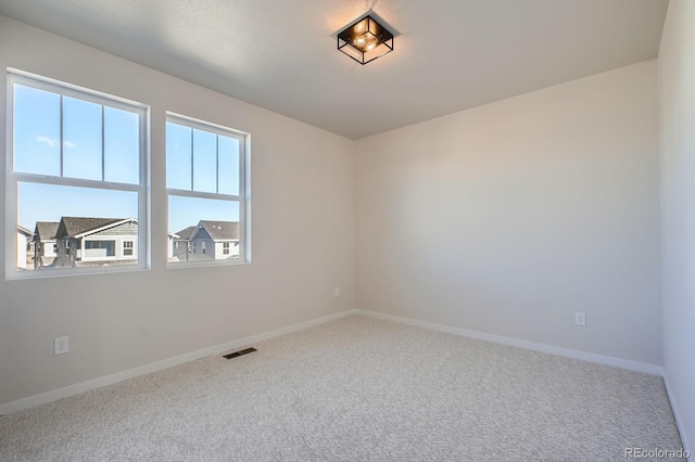 empty room with visible vents, baseboards, and carpet