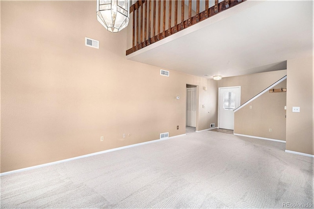 unfurnished living room featuring carpet flooring, visible vents, and baseboards