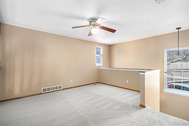 spare room featuring carpet, visible vents, ceiling fan, and baseboards