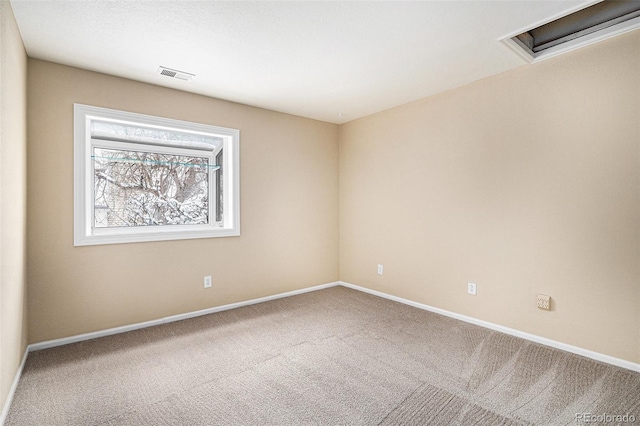 empty room with attic access, baseboards, visible vents, and carpet flooring