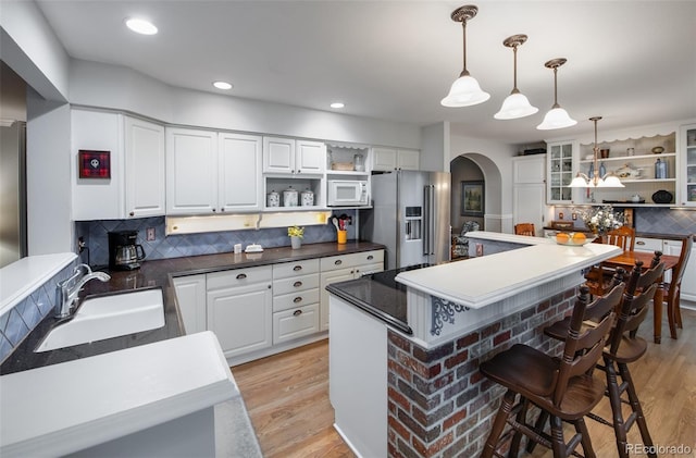 kitchen featuring sink, decorative light fixtures, white cabinetry, a center island, and high end fridge