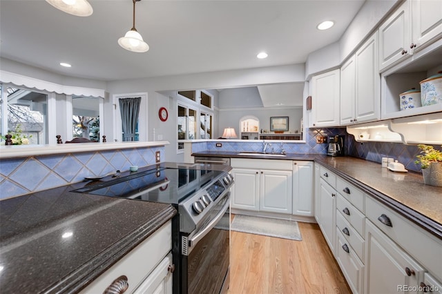 kitchen with sink, stainless steel electric range oven, white cabinets, and decorative backsplash