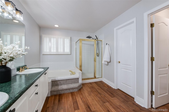 bathroom with plus walk in shower, wood-type flooring, and vanity