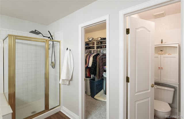 bathroom featuring toilet and a shower with door