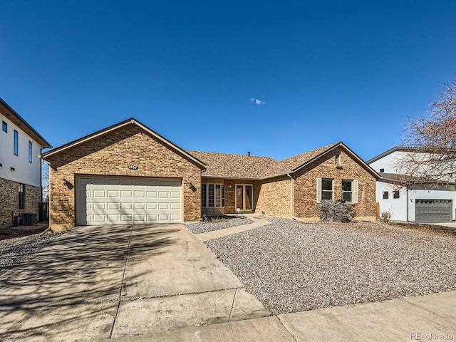 ranch-style house with a garage, central AC, concrete driveway, and brick siding