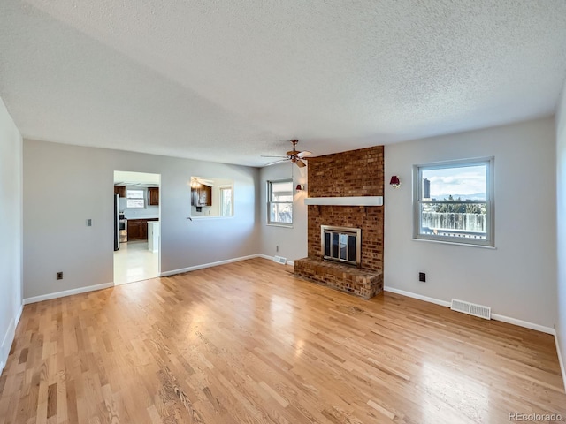 unfurnished living room featuring light wood-style floors, a wealth of natural light, and visible vents