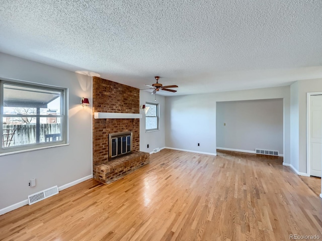 unfurnished living room with visible vents, a fireplace, and wood finished floors