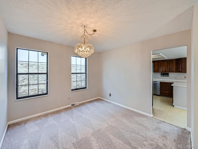 unfurnished room featuring light carpet, baseboards, visible vents, and a textured ceiling