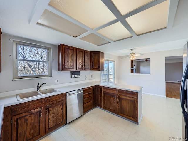 kitchen featuring light countertops, stainless steel dishwasher, a sink, coffered ceiling, and a peninsula