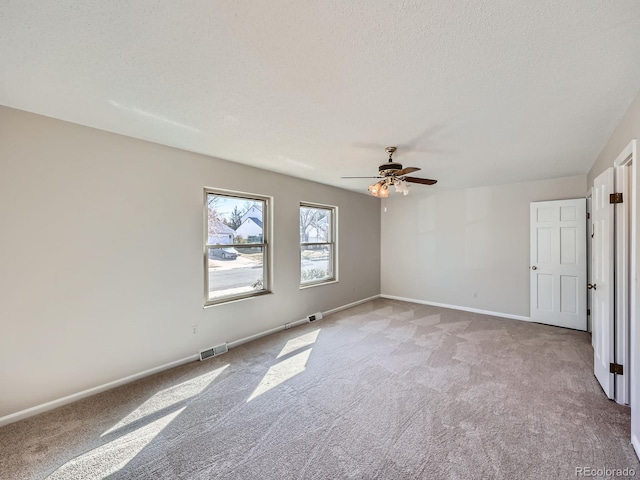 unfurnished room with carpet floors, visible vents, a textured ceiling, and baseboards