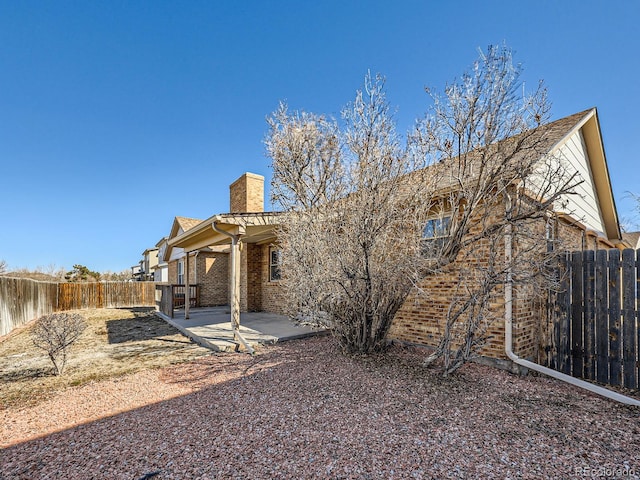 back of property with brick siding, a chimney, a patio area, and a fenced backyard