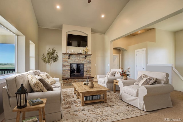 living room featuring a stone fireplace and high vaulted ceiling