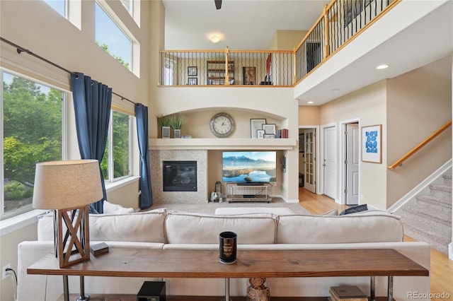 9158 Forest St, Firestone, CO 80504 - living area featuring a high ceiling, a glass covered fireplace, wood finished floors, and stairs