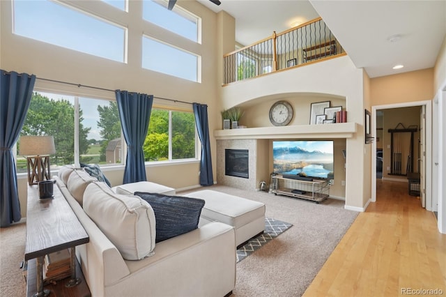 9158 Forest St, Firestone, CO 80504 - living area featuring a fireplace, wood finished floors, a towering ceiling, and baseboards
