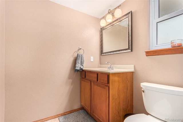 bathroom with baseboards, toilet, and vanity